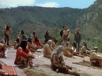 Movie still from “Broken Arrow” (1950), directed by Delmer Daves – A group of men sitting on the ground in front of a mountain; Wide shot, High angle