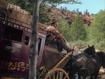 Movie still from “Broken Arrow” (1950), directed by Delmer Daves – A man sitting on the back of a horse drawn carriage; Wide shot, Low angle