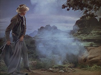 Movie still from “Broken Arrow” (1950), directed by Delmer Daves – A man standing in front of a fire in a field; Wide shot, Low angle