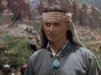 Movie still from “Broken Arrow” (1950), directed by Delmer Daves – A man with long black hair wearing a headband; Close Up shot, Over the shoulder angle