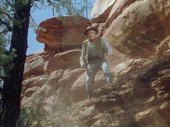 Movie still from “Broken Arrow” (1950), directed by Delmer Daves – A man is climbing a rock wall in the desert; Wide shot, Low angle