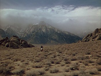 Movie still from “Broken Arrow” (1950), directed by Delmer Daves – A person riding a horse in the middle of the desert; Extreme Wide shot, High angle