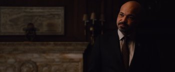 Movie still from “Broken City” (2013), directed by Allen Hughes – A man wearing a suit and tie in a room; Close Up shot, Over the shoulder angle