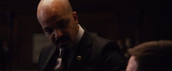 Movie still from “Broken City” (2013), directed by Allen Hughes – A man in a suit and tie looking at the camera; Close Up shot, Over the shoulder angle