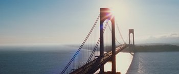 Movie still from “Broken City” (2013), directed by Allen Hughes – The sun is setting over a bridge over a body of water; Extreme Wide shot, High angle