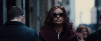 Movie still from “Broken City” (2013), directed by Allen Hughes – A person wearing sunglasses on a city street; Medium shot, Over the shoulder angle