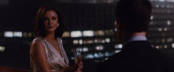 Movie still from “Broken City” (2013), directed by Allen Hughes – A woman holding a glass of wine in front of a man; Medium shot, Over the shoulder angle
