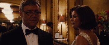 Movie still from “Broken City” (2013), directed by Allen Hughes – A man and a woman standing next to each other in front of lamps; Close Up shot, Over the shoulder angle