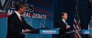 Movie still from “Broken City” (2013), directed by Allen Hughes – A man standing at a podium in front of a microphone; Medium shot, Low angle