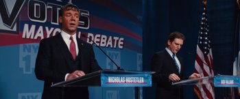 Movie still from “Broken City” (2013), directed by Allen Hughes – Two men in business suits are standing in front of a podium; Medium shot, Low angle