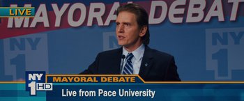Movie still from “Broken City” (2013), directed by Allen Hughes – A man in a suit and tie at a press conference; Close Up shot, High angle
