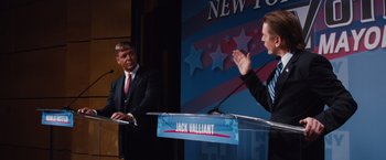 Movie still from “Broken City” (2013), directed by Allen Hughes – A man and a woman standing in front of microphones; Medium shot, Over the shoulder angle