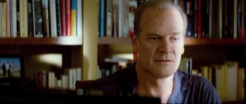 Movie still from “Broken Embraces” (2009), directed by Pedro Almodóvar – A person sitting in a room; Close Up shot, Over the shoulder angle