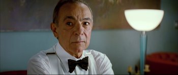 Movie still from “Broken Embraces” (2009), directed by Pedro Almodóvar – An older man wearing a white shirt and black bow tie; Close Up shot, Low angle