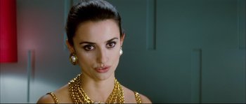 Movie still from “Broken Embraces” (2009), directed by Pedro Almodóvar – A woman wearing a gold necklace and earrings; Close Up shot, Over the shoulder angle