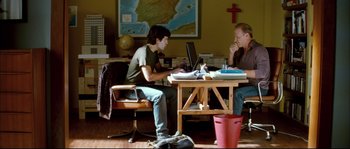 Movie still from “Broken Embraces” (2009), directed by Pedro Almodóvar – Two people sitting at a table with a laptop; Wide shot, Over the shoulder angle