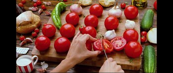Movie still from “Broken Embraces” (2009), directed by Pedro Almodóvar – A person slicing tomatoes on top of a cutting board; Extreme Close Up shot, Overhead angle