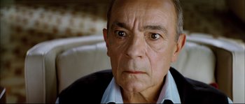 Movie still from “Broken Embraces” (2009), directed by Pedro Almodóvar – An older man with a serious look on his face; Close Up shot, High angle