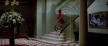 Movie still from “Broken Embraces” (2009), directed by Pedro Almodóvar – A woman in a red dress standing at the bottom of a staircase; Wide shot, High angle