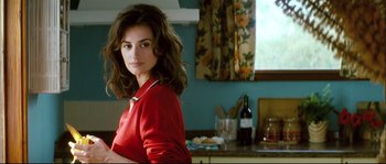 Movie still from “Broken Embraces” (2009), directed by Pedro Almodóvar – A woman standing in a kitchen with a bottle of wine in front of her; Medium shot, Over the shoulder angle
