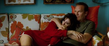 Movie still from “Broken Embraces” (2009), directed by Pedro Almodóvar – A man and a woman laying on a couch together; Medium shot, High angle