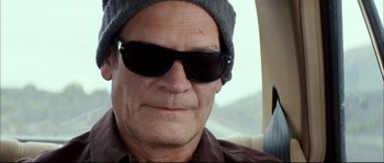 Movie still from “Broken Embraces” (2009), directed by Pedro Almodóvar – A person wearing a hat and sunglasses; Close Up shot, Low angle