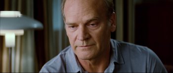 Movie still from “Broken Embraces” (2009), directed by Pedro Almodóvar – An older man with a goatee looking at the camera; Close Up shot, Over the shoulder angle