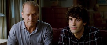 Movie still from “Broken Embraces” (2009), directed by Pedro Almodóvar – Two men sitting next to each other on a couch; Close Up shot, Over the shoulder angle