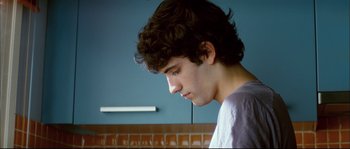Movie still from “Broken Embraces” (2009), directed by Pedro Almodóvar – A young man is looking down at his face; Close Up shot, Over the shoulder angle