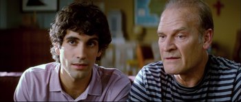 Movie still from “Broken Embraces” (2009), directed by Pedro Almodóvar – Two men sitting next to each other in front of a window; Close Up shot, Over the shoulder angle