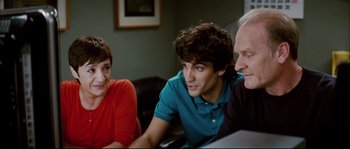Movie still from “Broken Embraces” (2009), directed by Pedro Almodóvar – A young man sitting next to an older man and woman; Medium shot, Over the shoulder angle