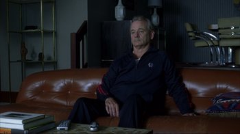 Movie still from “Broken Flowers” (2005), directed by Jim Jarmusch – A man sitting on top of a brown leather couch; Medium shot, High angle