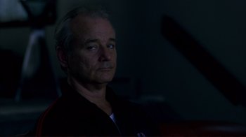 Movie still from “Broken Flowers” (2005), directed by Jim Jarmusch – A man in a black shirt is sitting in a dark room; Close Up shot, Low angle