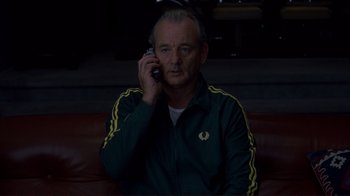 Movie still from “Broken Flowers” (2005), directed by Jim Jarmusch – A man sitting on a couch talking on a cell phone; Medium shot, Low angle
