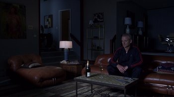 Movie still from “Broken Flowers” (2005), directed by Jim Jarmusch – A man sitting on a couch in a living room; Wide shot, High angle