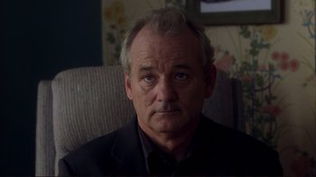 Movie still from “Broken Flowers” (2005), directed by Jim Jarmusch – A man sitting in a chair looking at the camera; Close Up shot, Over the shoulder angle