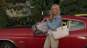 Movie still from “Broken Flowers” (2005), directed by Jim Jarmusch – A woman standing in front of a red car holding shopping bags; Medium shot, Low angle