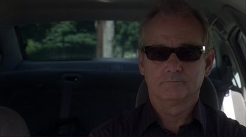 Movie still from “Broken Flowers” (2005), directed by Jim Jarmusch – An older man wearing sunglasses sitting in the back of a car; Close Up shot, Over the shoulder angle
