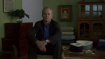 Movie still from “Broken Flowers” (2005), directed by Jim Jarmusch – A man in a suit sitting in a living room; Medium shot, Low angle