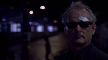 Movie still from “Broken Flowers” (2005), directed by Jim Jarmusch – A person wearing sunglasses and a bandage on his head; Close Up shot, Low angle