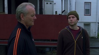 Movie still from “Broken Flowers” (2005), directed by Jim Jarmusch – Two men standing next to each other in front of a house; Medium shot, Over the shoulder angle