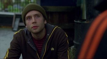 Movie still from “Broken Flowers” (2005), directed by Jim Jarmusch – A young man wearing a green hat and a brown jacket; Close Up shot, Over the shoulder angle