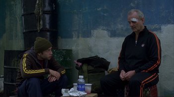 Movie still from “Broken Flowers” (2005), directed by Jim Jarmusch – Two men sitting on the ground talking to each other; Medium shot, Over the shoulder angle