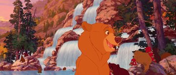 Movie still from “Brother Bear” (2003), directed by Robert Walker – A brown bear standing in front of a waterfall; Wide shot, Low angle