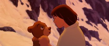 Movie still from “Brother Bear” (2003), directed by Robert Walker – A woman holding a bear in front of a mountain; Close Up shot, Over the shoulder angle