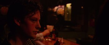 A man sitting at a table in front of a bottle of beer