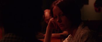 A woman sitting at a table in a dimly - lit room