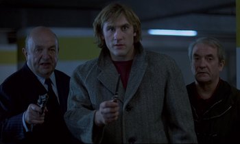 A man in a gray jacket holding a pen