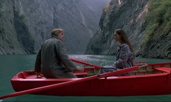 A man and a woman sitting in a boat on a river