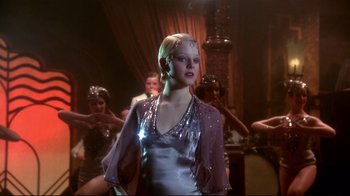 A group of people in a room with a woman in a silver dress